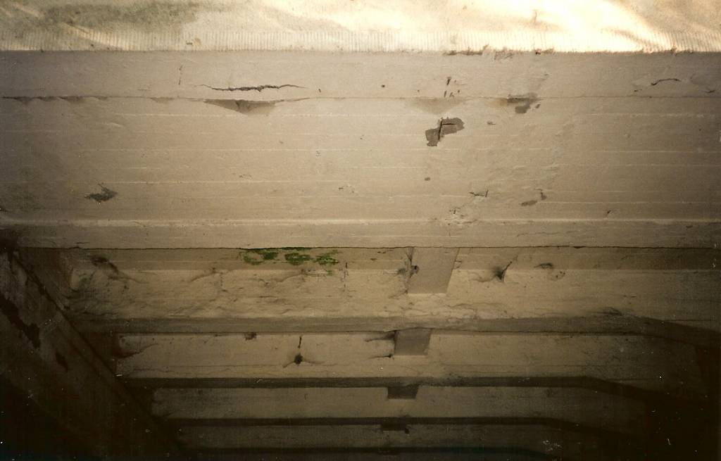 foto:archiwum  zditm 1995, Belka skrajna południowa na wysokosci pierwszego przęsła. Widoczne spękania betonu na spodzie belki, brak otuliny prętów płyty, zacieki pomiędzy belkami głównymi nr 12 i 13.